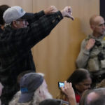 
              A man gives the thumbs down to the Maricopa County Board of Supervisors during their general election canvass meeting, Monday, Nov. 28, 2022, in Phoenix. (AP Photo/Matt York)
            