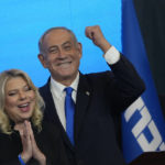 
              Former Israeli Prime Minister and the head of Likud party, Benjamin Netanyahu and his wife Sara gesture after first exit poll results for the Israeli Parliamentary election at his party's headquarters in Jerusalem, Wednesday, Nov. 2, 2022. (AP Photo/Tsafrir Abayov)
            