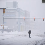 
              A person crosses Ellicott Street as snow falls Friday, Nov. 18, 2022, in Buffalo, N.Y.  A dangerous lake-effect snowstorm paralyzed parts of western and northern New York, with nearly 2 feet of snow already on the ground in some places and possibly much more on the way.  (AP Photo/Joshua Bessex)
            