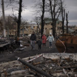 
              FILE - A family walks amid destroyed Russian tanks in Bucha, on the outskirts of Kyiv, Ukraine, Wednesday, April 6, 2022. Ukrainian prosecutors now say those responsible for the violence at 144 Yablunska were soldiers from the 76th Guards Airborne Assault Division, under the battlefield command of Alexander Chaiko, a colonel general known for his brutality as leader of Russia's troops in Syria. (AP Photo/Felipe Dana, File)
            