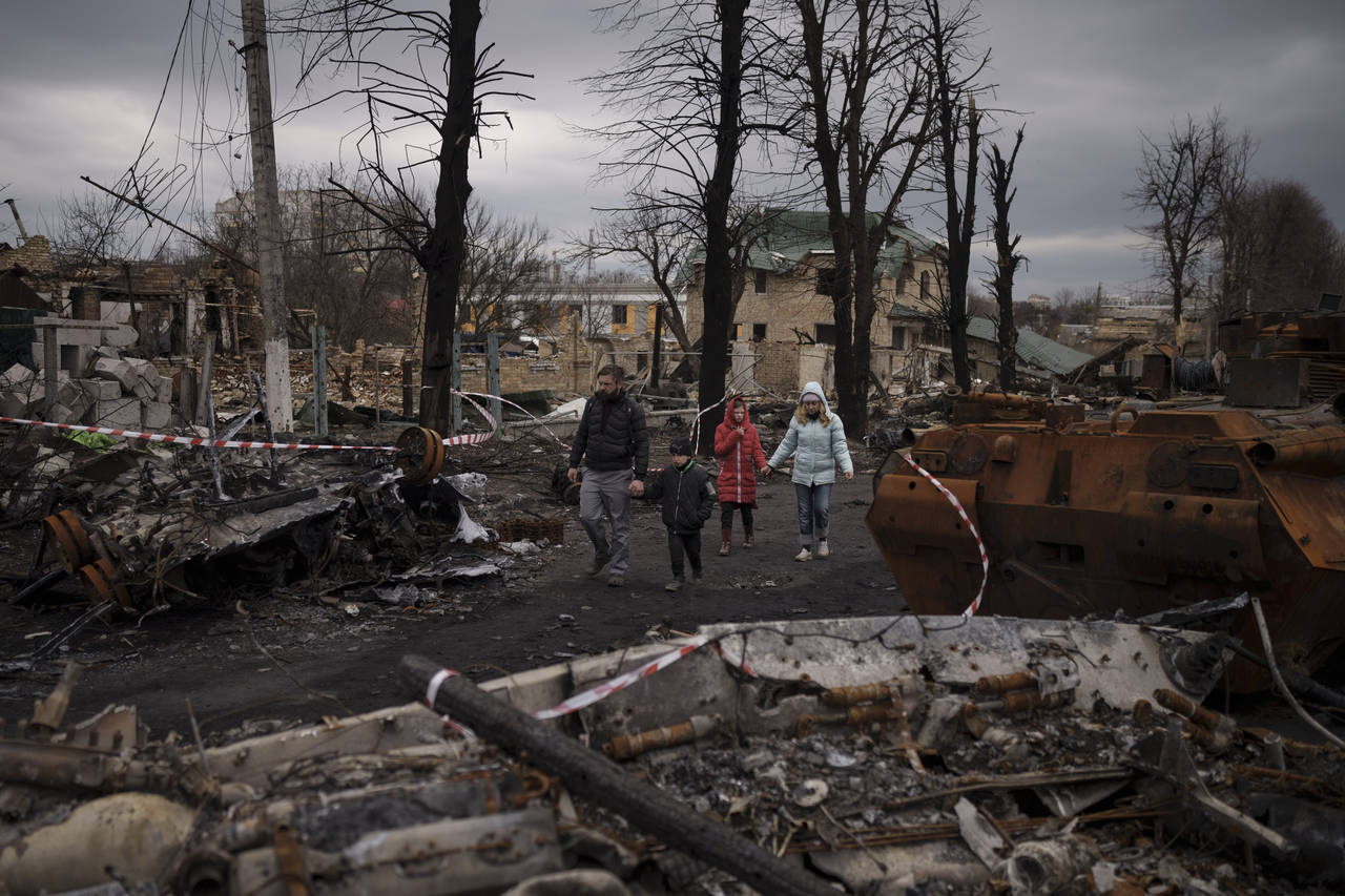 FILE - A family walks amid destroyed Russian tanks in Bucha, on the outskirts of Kyiv, Ukraine, Wed...
