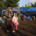 
              People displaced by Monday's earthquake walk near temporary shelters in Cianjur, West Java, Indonesia, Thursday, Nov. 24, 2022. The 5.6 magnitude earthquake left hundreds dead, injures and missing as buildings crumbled and terrified residents ran for their lives on Indonesia's main island of Java. (AP Photo/Tatan Syuflana)
            