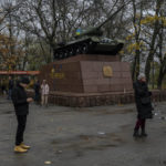 
              Residents talk on the phone next to a monument with a recently paint Ukrainian flag in Kherson, southern Ukraine, Sunday, Nov. 20, 2022. The Russian withdrawal from the only provincial capital it gained in nine months of war was one of Moscow most significant battlefield losses. Now that its troops hold a new front line, the Ukrainian military said through a spokesman, the army is planning its next move. (AP Photo/Bernat Armangue)
            