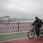 
              A man rides a bike on a bridge over Dnipro river in Kyiv, Ukraine, Friday, Nov. 11, 2022. (AP Photo/Andrew Kravchenko)
            
