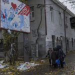 
              Residents gather below a billboard next to the remains of Russian posters in Kherson, in southern Ukraine, on Thursday, November 17, 2022. (AP Photo/Bernat Armangue)
            