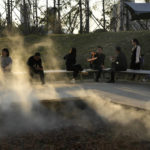 
              Residents rest on benches near a permeable section as mist is sprayed at the "Fish Tail" sponge park that's built on a former coal ash dump site in Nanchang in north-central China's Jiangxi province on Sunday, Oct. 30, 2022. The concept of the park involves creating and expanding parks and ponds within urban areas to prevent flooding and absorb water for times of drought. (AP Photo/Ng Han Guan)
            