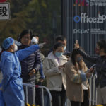 
              A woman, right, wearing a face mask shows her health check QR code as she and others line up to get their routine COVID-19 throat swabs at a coronavirus testing site in Beijing, Tuesday, Nov. 8, 2022. Police in northeastern China say seven people have been arrested following a clash between residents and authorities enforcing COVID-19 quarantine restrictions. (AP Photo/Andy Wong)
            