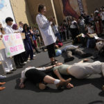 
              Demonstrators participate in a "die-in" advocating for the 1.5 degree warming goal to survive at the COP27 U.N. Climate Summit, Wednesday, Nov. 16, 2022, in Sharm el-Sheikh, Egypt. (AP Photo/Peter Dejong)
            