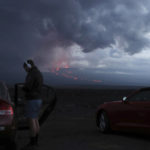 
              Spectators watch the lava flow down the mountain from the Mauna Loa eruption, Tuesday, Nov. 29, 2022, near Hilo, Hawaii. (AP Photo/Marco Garcia)
            