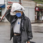 
              A pedestrian protects his hat from the rain with a plastic bag in the Chinatown district of Los Angeles, Monday, Nov. 7, 2022. A new Pacific storm is bringing snow, rain and wind to California. It’s the second significant storm this month for the state, which remains deep in drought. (AP Photo/Damian Dovarganes)
            