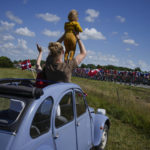 
              Spectators watch from a classic Citroen 2CV car as the pack passes during the second stage of the Tour de France cycling race over 202.5 kilometers (125.8 miles) with start in Roskilde and finish in Nyborg, Denmark, Saturday, July 2, 2022. (AP Photo/Daniel Cole)
            