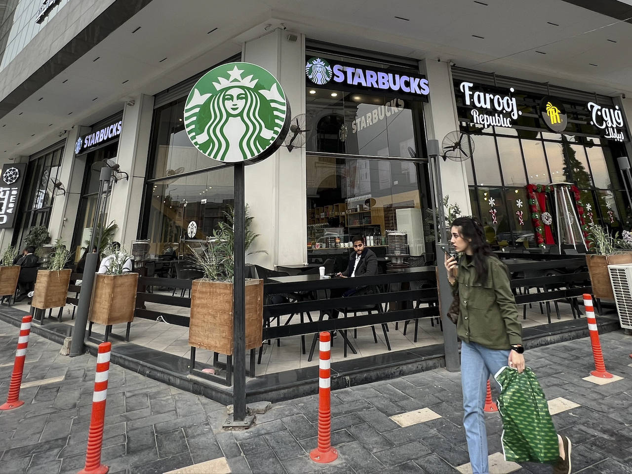 A woman walks by an unlicensed Starbucks cafe in Baghdad, Iraq, Wednesday, Dec. 21, 2022. Real Star...