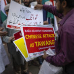 
              A member of Indian Islamist group Raza Academy distributes placards ahead of a protest against China in Mumbai, India, Tuesday, Dec. 13, 2022. Soldiers from India and China clashed last week along their disputed border, India's defense minister said Tuesday, in the latest violence along the contested frontier since June 2020, when troops from both countries engaged in a deadly brawl. (AP Photo/Rafiq Maqbool)
            