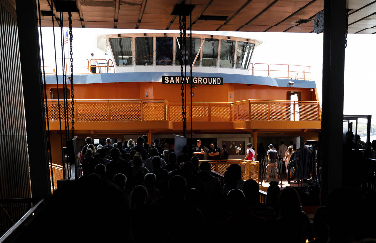 FILE - People board the Staten Island Ferry boat Sandy Ground in the Whitehall Terminal, Aug. 4, 20...