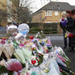 
              Woman lay flowers among the tributes near to Babbs Mill Park in Kingshurst, Solihull, Tuesday Dec. 13, 2022 after the deaths of three boys aged eight, 10 and 11 who fell through ice into a lake in the West Midlands. (Jacob King/PA via AP)
            