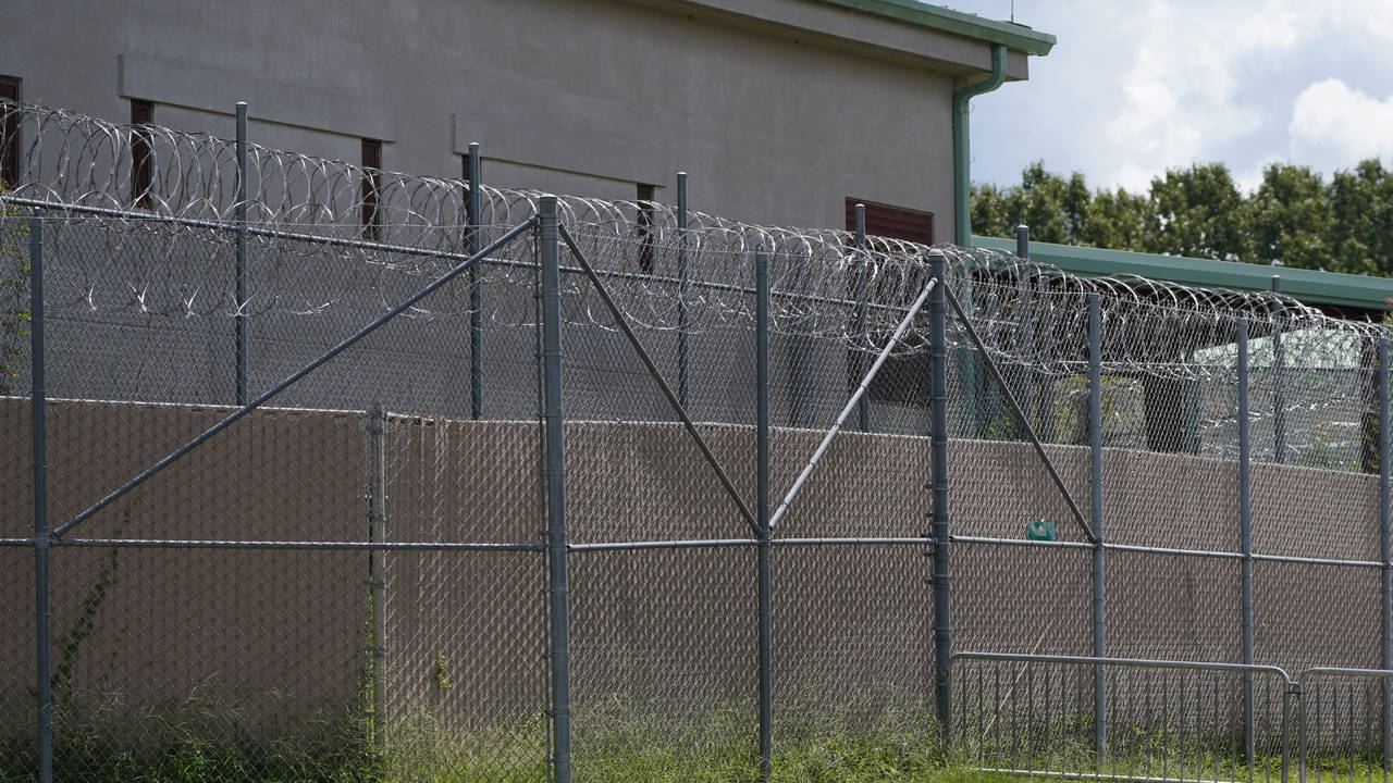 FILE - Rolls of razor wire line the top of the security fencing at the Raymond Detention Center in ...