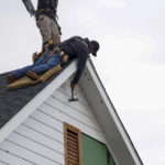 
              Antonio Rios, bottom, and Noel Enriquez work to patch the roof and siding of a home after a possible tornado in Grapevine, Texas, Tuesday, Dec. 13, 2022. (Elías Valverde II/The Dallas Morning News via AP)
            