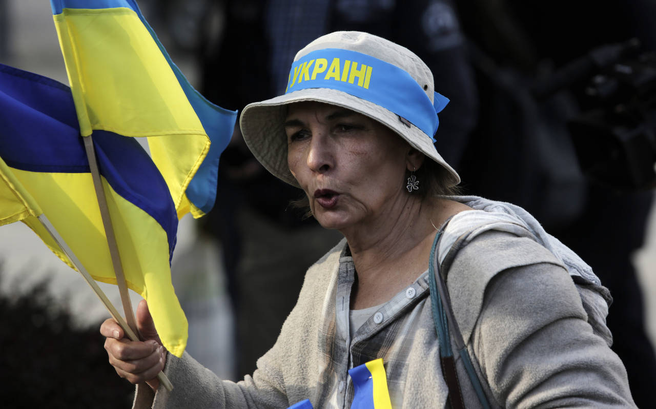 FILE - A Ukrainian supporter shouts slogans as she holds Ukrainian flags in front of Bulgarian Parl...