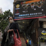 
              A woman wearing mask walks past an outdoor screen displaying a live broadcast of the memorial service for late former Chinese President Jiang Zemin in Hong Kong, Tuesday, Dec. 6, 2022. A formal memorial service was held Tuesday at the Great Hall of the People, the seat of the ceremonial legislature in the center of Beijing. (AP Photo/Vernon Yuen)
            