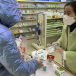 
              Pharmacist Zhu Qianqian prepares medication for a customer at a pharmacy in Beijing, Wednesday, Dec. 14, 2022. China's National Health Commission scaled down its daily COVID-19 report starting Wednesday in response to a sharp decline in PCR testing since the government eased antivirus measures after daily cases hit record highs. (AP Photo/Dake Kang)
            