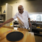 
              Mani Bhushan, owner of Taco Ocho, puts out table menus at one of his restaurants in McKinney, Texas, Friday, Nov. 11, 2022. Bhushan struggles to hire workers in the McKinney location, which opened in July 2021. He said many workers can't afford to live in this upscale suburb and have to travel from elsewhere. (AP Photo/LM Otero)
            