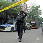 
              A police officer gestures at the crowd to move back as he guards a road leading to a police station where a bomb exploded in Bandung, West Java, Indonesia, Wednesday, Dec. 7, 2022. A man blew himself up Wednesday at a police station on Indonesia's main island of Java in what appeared to be the latest in a string of suicide attacks in the world's most populous Muslim nation. (AP Photo/Kholid Parmawinata)
            