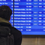 
              A passenger check flight departure schedules, some showing cancellations, at the Delta terminal at Laguardia Airport, Friday Dec. 23, 2022, in New York. (AP Photo/Bebeto Matthews)
            