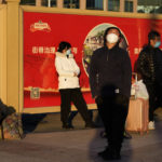 
              Residents wearing masks rest near propaganda posters on an empty plaza outside the train station in Beijing, Thursday, Dec. 8, 2022. In a move that caught many by surprise, China announced a potentially major easing of its rigid "zero-COVID" restrictions, without formally abandoning the policy altogether. (AP Photo/Ng Han Guan)
            