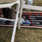 
              FILE - A man sits with his feet on a doormat critical of President Joe Biden during the ReAwaken America Tour at Cornerstone Church in Batavia, N.Y., Aug. 13, 2022. (AP Photo/Carolyn Kaster, File)
            