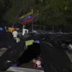 
              A Venezuelan national flag flies over a makeshift camp of migrants on a river bank in  Matamoros, Mexico, Thursday, Dec. 22, 2022. (AP Photo/Fernando Llano)
            