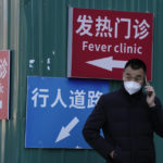 
              A man wearing a mask talks on his phone near signs directing visitors to the fever clinic at a hospital in Beijing, Saturday, Dec. 10, 2022. A rash of COVID-19 cases in schools and businesses were reported Friday in areas across China after the ruling Communist Party loosened anti-virus rules as it tries to reverse a deepening economic slump. (AP Photo/Ng Han Guan)
            