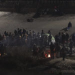 Migrants gather near a camp fire near the U.S.-Mexico border as seen from Ciudad Juarez, Mexico, Tuesday, Dec. 20, 2022. The U.S. Supreme Court issued a temporary order to keep pandemic-era limits on asylum-seekers in place, though it could be brief, as conservative-leaning states push to maintain a measure that allows officials to expel many but not all asylum-seekers. (AP Photo/Christian Chavez)