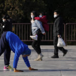 
              Visitors wearing masks watch as a resident walks on all four limbs as a form of exercise in the Temple of Heaven park in Beijing, Thursday, Dec. 8, 2022. In a move that caught many by surprise, China announced a potentially major easing of its rigid "zero-COVID" restrictions, without formally abandoning the policy altogether. (AP Photo/Ng Han Guan)
            
