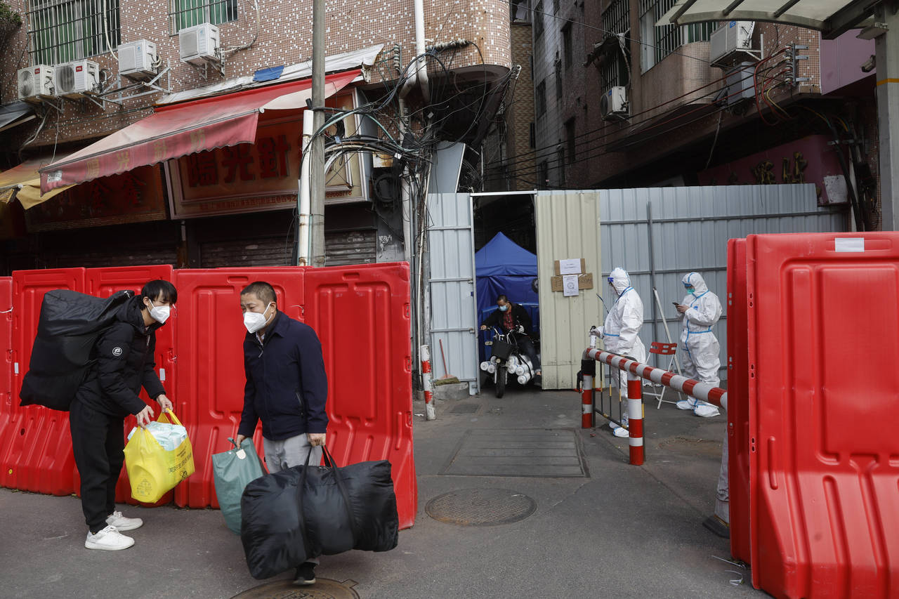 Migrant workers with their belongings leave a barricaded village after authorities' easing of COVID...