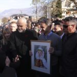 
              Greek Prime Minister Kyriakos Mitsotakis holds a painting as his Albanian counterpart Edi Rama, left, shakes hands with residents during their visit to ethnic Greek minority regions, in Dervican village, southern Albania, Thursday, Dec. 22, 2022. Relations between Greece and post-communist Albania have been at times uneasy but have improved in recent years, largely over minority rights. (AP Photo/Franc Zhurda)
            