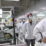 
              FILE - Workers line up to get tested for COVID-19 at the Foxconn factory in Wuhan in central China's Hubei province on Aug. 5, 2021. Foxconn, the company that assembles Apple Inc.’s iPhones, has announced it is easing COVID-19 restrictions at its largest factory, in Zhengzhou, central China, that led thousands of workers to quit and drastically slowed production. (Chinatopix via AP, File)
            