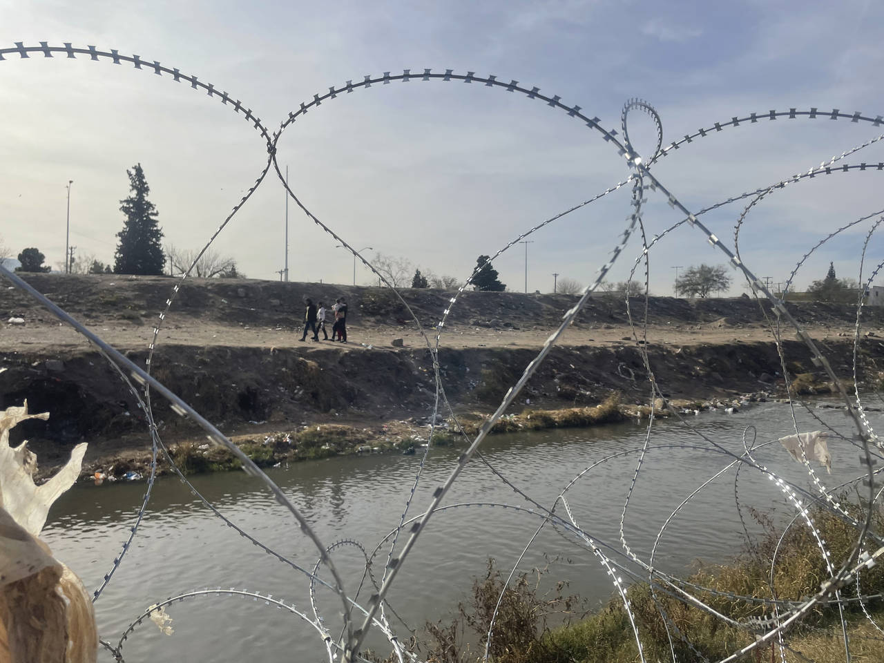 A family is seen on the Mexican side of the Rio Grande River through the concertina wire placed ear...