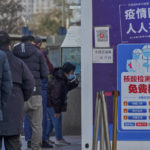 
              A woman shows her health check QR code as residents line up to get their routine COVID-19 throat swabs at a coronavirus testing site although authorities start easing some of the anti-virus controls in Beijing, Wednesday, Dec. 7, 2022. China has announced new measures rolling back COVID-19 restrictions, including limiting lockdowns and testing requirements. (AP Photo/Andy Wong)
            