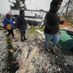 
              People walk through the rubble after a tornado tore through the area in Killona, La., about 30 miles west of New Orleans in St. James Parish, Wednesday, Dec. 14, 2022. (AP Photo/Gerald Herbert)
            