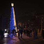 
              People gather around a Christmas tree decorated with the colors of the Ukrainian national flag at Sophia square in Kyiv, Ukraine, Friday, Dec. 23, 2022. Ukrainians can enjoy only some blue and yellow gleam barely lighting up a more modest Christmas tree at a traditional square as authorities have imposed some restrictions and schedule power cuts, meaning that there's no traditional gleaming city during the Christmas season. (AP Photo/Felipe Dana)
            
