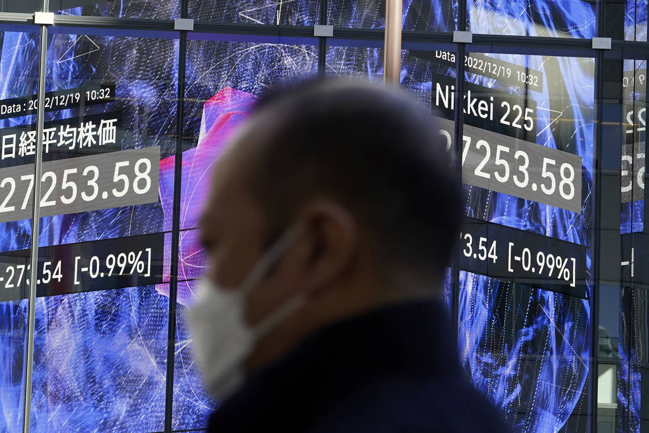 A person stands near an electronic stock board showing Japan's Nikkei 225 index at a securities fir...