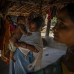 
              Phagni Poyam, 23, a nine months pregnant woman, dresses her one-year-old boy, Dilesh, as they get ready to shift to a health center in a motorbike ambulance in Kodoli, a remote village near Orchha in central India's Chhattisgarh state, Nov. 15, 2022. These ambulances, first deployed in 2014, reach inaccessible villages to bring pregnant women to an early referral center, a building close to the hospital where expectant mothers can stay under observation, routinely visit doctors if needed until they give birth. Since then the number of babies born in hospitals has doubled to a yearly average of about 162 births each year, from just 76 in 2014. The state has one of the highest rates of pregnancy-related deaths for mothers in India, about 1.5 times the national average, with 137 pregnancy related deaths for mothers per 100,000 births. (AP Photo/Altaf Qadri)
            