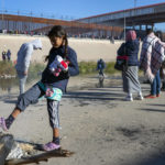 
              A migrant child tries to warm her feet with what remains of a campfire at the southern bank of the Rio Grande in Ciudad Juarez, Mexico, on Wednesday, Dec. 21, 2022. (AP Photo/Andres Leighton)
            