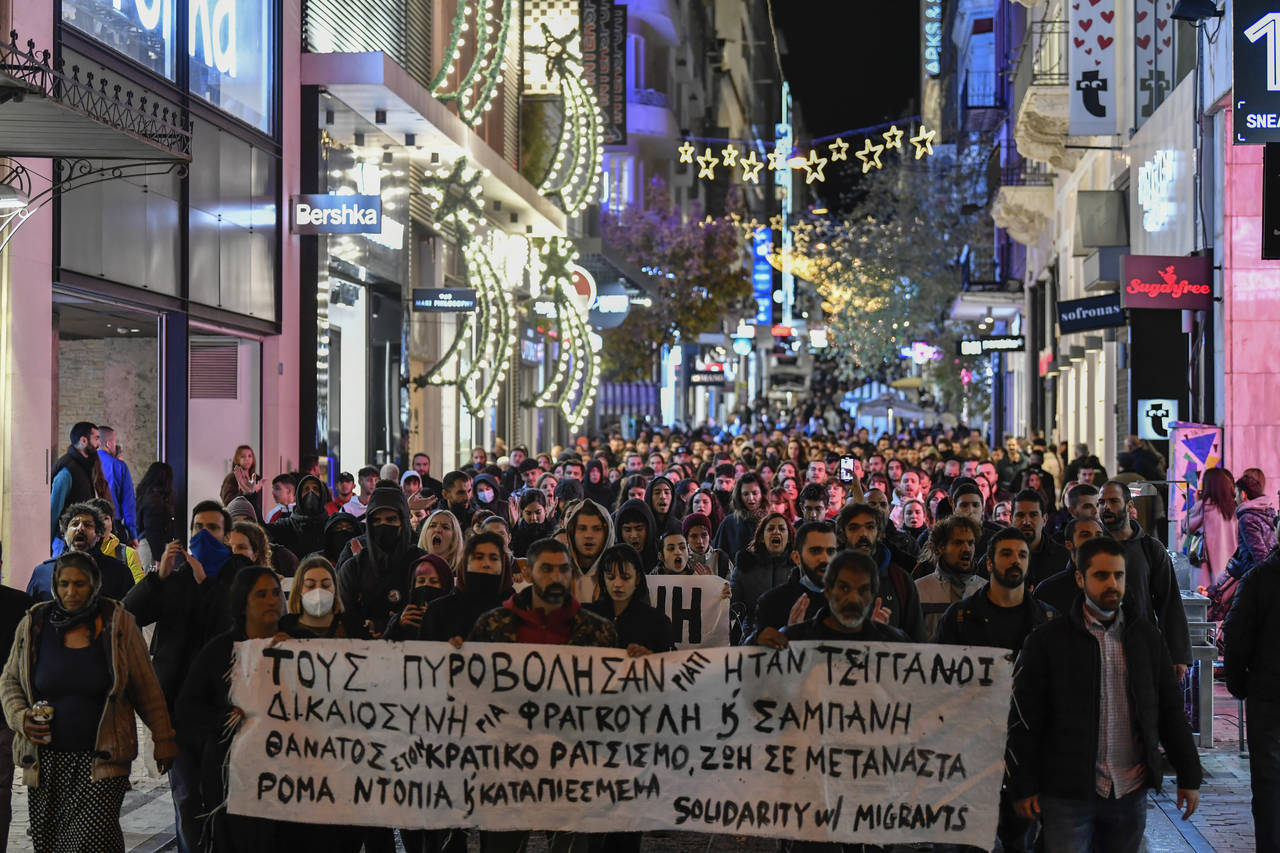 Protesters hold a banner which reads in Greek "they shot them because they were Roma" as they prote...