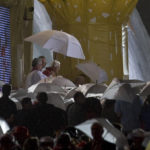 
              FILE - Pope Benedict XVI is protected from the rain by an umbrella in Cuatro Vientos, near to Madrid, Spain, on Saturday, Aug. 20, 2011. He was the reluctant pope, a shy bookworm who preferred solitary walks in the Alps and Mozart piano concertos to the public glare and majesty of Vatican pageantry. When Cardinal Joseph Ratzinger became Pope Benedict XVI and was thrust into the footsteps of his beloved and charismatic predecessor, he said he felt a guillotine had come down on him. The Vatican announced Saturday Dec. 31, 2022 that Benedict, the former Joseph Ratzinger, had died at age 95. (AP Photo/Alvaro Barrientos, File)
            