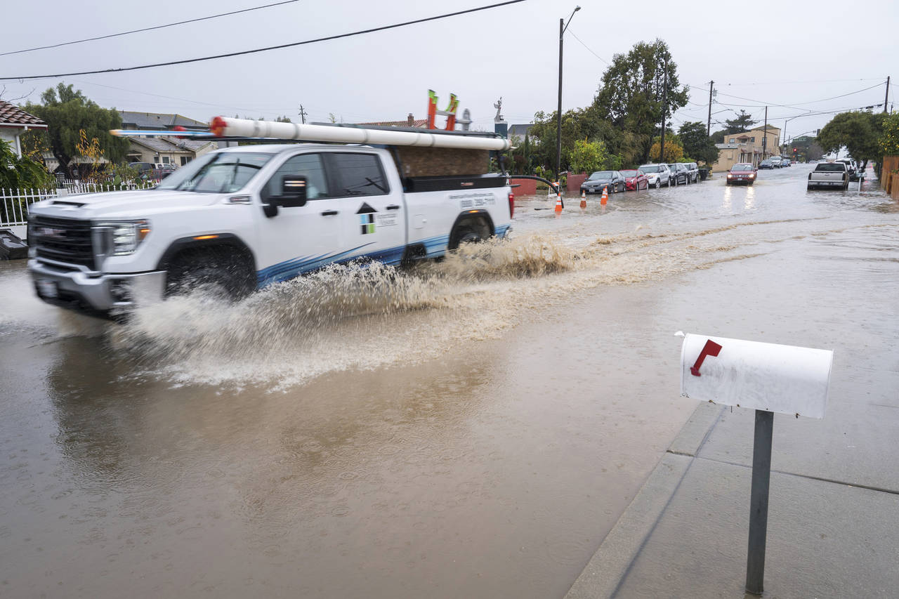 A truck drives through a flooded intersection of E Bolivar Street in Salinas, Calif., Tuesday, Dec....