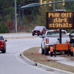 
              Workers set up an automated display warning drivers on NC211 of the power outage in the area and how to approach the upcoming intersections in Southern Pines, N.C., Monday, Dec. 5, 2022. (AP Photo/Karl B DeBlaker)
            