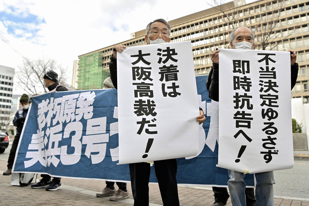 Petitioners display banners in front of Osaka District Court in Osaka, western Japan Tuesday, Dec. ...
