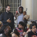 
              The Rev. Brian Strassburger, a Jesuit priest, talks with Rose, a Haitian migrant holding her 1-year-old son, in the Casa del Migrante shelter in Reynosa, Mexico, on Dec. 15, 2022. Strassburger and two fellow Jesuit priests go across the border twice weekly to celebrate Mass and bring some comfort at the shelter, which is at more than double its capacity as migrants cram this border city. (AP Photo/Giovanna Dell'Orto)
            