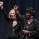 
              Gloria Steinem, left, and Dorothy Pitman Hughes raise their fists together, resembling a photograph taken during the height of their activism together, at the Lazarra Theatre at the University of North Florida in Jacksonville, Fla., during an speaking event on March 10, 2011. Hughes, a pioneering Black feminist, child welfare advocate and activist who co-founded Ms. Magazine with Steinem, formed a powerful speaking partnership with her and appeared with her in one of the most iconic photos of the feminist movement, has died. Hughes died Dec. 1, 2022, in Tampa, Fla.  She was 84. (Jon M. Fletcher/The Florida Times-Union via AP)
            